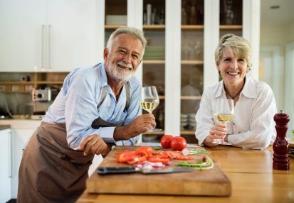 Couple standing in kitchen drinking white wine