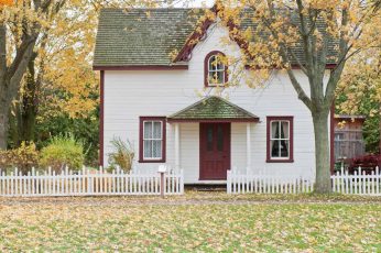 Small white home with red trim and picket fence.